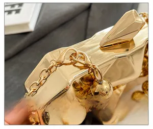 Close-up of golden geometric hard shell evening clutch bag with premium metal hardware