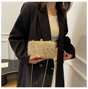 Detail of champagne gold sequin evening clutch with leaf pattern and pearl top handle