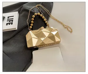 Detail of gold geometric hardshell evening clutch with beaded handle and chain strap