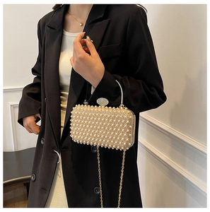 Close-up of pearl evening bag with oval rhinestone buckle and gold metal chain strap