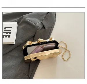 Detail of golden geometric hardshell evening bag showing capacity for phone and lipstick