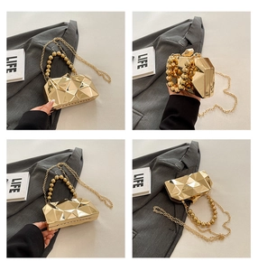 Detail view of gold geometric hard shell evening bag with beaded handle and chain strap
