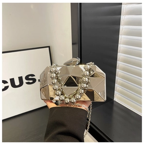 Close-up of a silver geometric evening clutch bag with large metallic bead handle