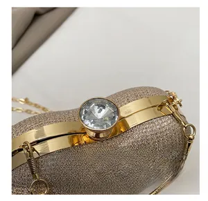 Detailed close-up of champagne glitter evening bag with gold metal frame and crystal clasp
