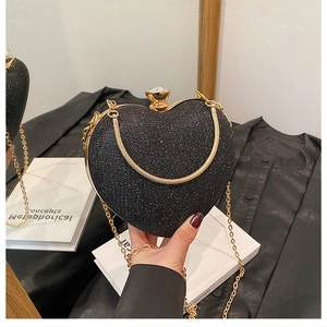 Macro view of heart-shaped evening bag featuring black glitter and gold metal trim