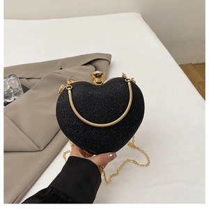 Detail of a black heart-shaped glitter evening bag with gold chain and metal lock