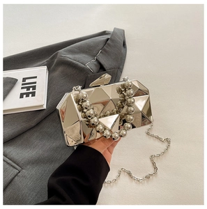 Detail of silver geometric hardshell clutch with beaded handle and metal chain strap