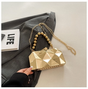 Close-up of golden geometric evening bag with pearl handle and chain on stylish blazer