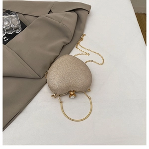 Close-up of heart-shaped glitter evening bag with jewel lock and gold chain strap