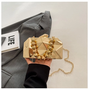 Detail of golden geometric quilted evening bag with beaded handle and metal chain