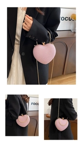 Detail of pink heart-shaped glitter clutch bag with gold handle and chain strap