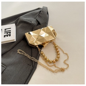 Macro detail of golden geometric metal evening bag with bead handle and chain strap