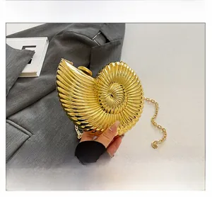 Close-up of golden nautilus-shaped acrylic clutch with radial metal texture and chain