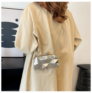 Close-up of a silver geometric metallic evening bag with a sleek chain strap on a model