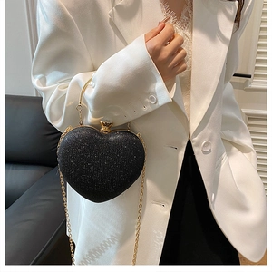 Detailed close-up of glittery heart-shaped evening bag with golden round handle and chain
