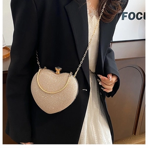 Detail of heart-shaped evening bag with gold sequins and crossbody chain on model