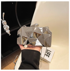 Macro detail of silver geometric evening clutch bag with mirrored metallic finish and chain