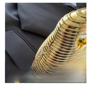 Detailed close-up of golden ripple clutch hardware with metal lobster clasp and chain