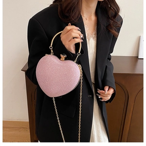 Close-up of pink glitter heart-shaped bag with gold metal handle and chain strap detail
