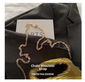 Close-up of elegant gold metal chain strap on a textured ripple acrylic evening bag