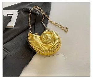 Detail of creative golden seashell chain bag styled on grey suit fabric with smartphone