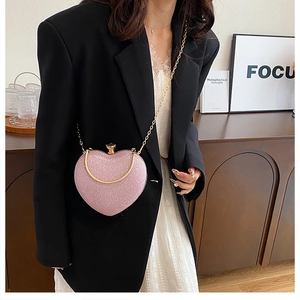 Close-up of heart-shaped evening bag with pink glitter finish and golden chain strap
