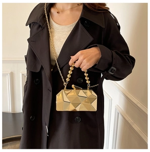 Detail of gold geometric evening bag with faceted metal texture and beaded handle