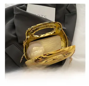 Detail view of gold wavy metal clutch bag showing internal space for phone and makeup