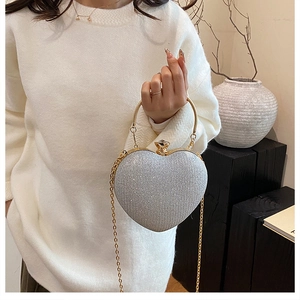 Detail of silver glitter heart-shaped evening bag with gold handle and chain strap