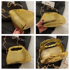 Detail view of gold wavy acrylic clutch bag showing internal space and chain strap