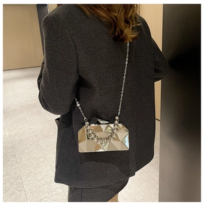 Detailed view of a silver geometric evening bag with a beaded handle and metallic chain