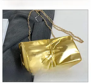 Detail of gold wrinkled acrylic clutch with metallic mirror finish and chain strap