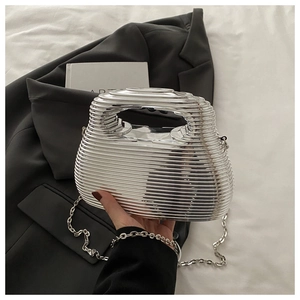 Detail of silver wavy cage handbag with metal chain strap against a black blazer