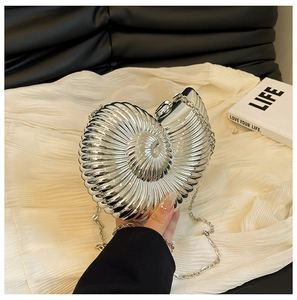 Detailed view of silver seashell-shaped clutch with radial grooves and metallic chain