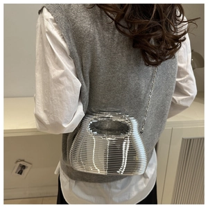 Detail of silver metallic striped acrylic bag with chain strap and hollow handle design