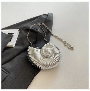 Macro shot of silver metallic nautilus shell clutch bag on a grey designer blazer