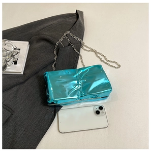 Detail of metallic cyan acrylic box bag with pleated texture and silver chain strap