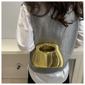 Detail of gold acrylic clutch with wave pattern and metallic chain for evening wear