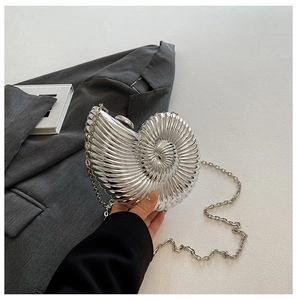 Macro shot of silver conch shell clutch with metallic texture and sleek chain strap