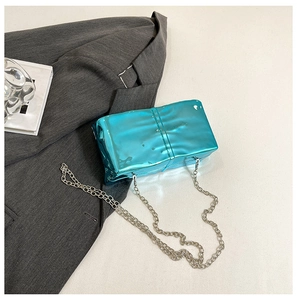 Detail of blue mirror acrylic box bag with silver chain and wavy textured surface