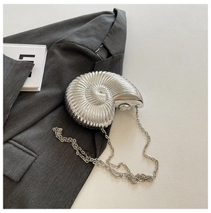 Macro detail of silver nautilus shell evening bag with luxury metallic texture and chain