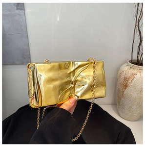 Detail of gold metallic clutch bag featuring artistic pleated texture and metal chain