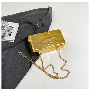 Detail of gold metallic crossbody clutch with unique pleated texture and chain strap