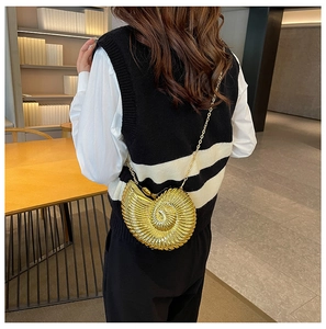 Detailed view of metallic gold nautilus shell clutch bag with elegant chain strap on a model