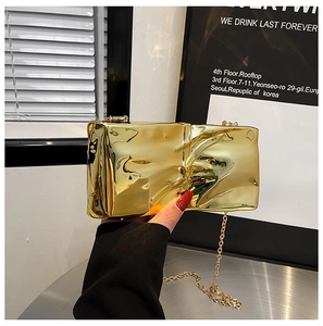 Detail of gold mirror acrylic box bag featuring a unique crumpled paper bag design with chain