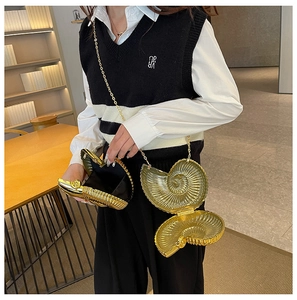 Macro view of golden conch clutch bag featuring metallic texture and black inner lining