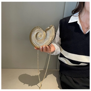 Close-up of golden nautilus shell clutch bag with metallic texture and thin chain strap