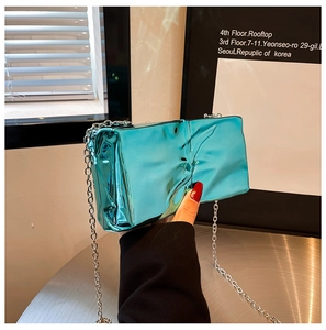Detail of blue liquid metal crossbody bag with textured wrinkles and silver chain strap