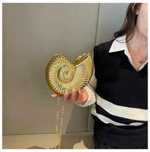 Close-up of golden nautilus shell clutch bag with spiral texture and chain strap