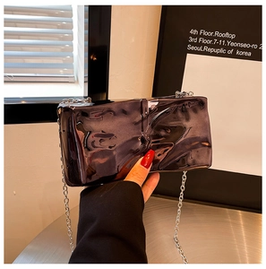 Detailed view of silver metallic acrylic clutch with wavy texture and fine chain strap